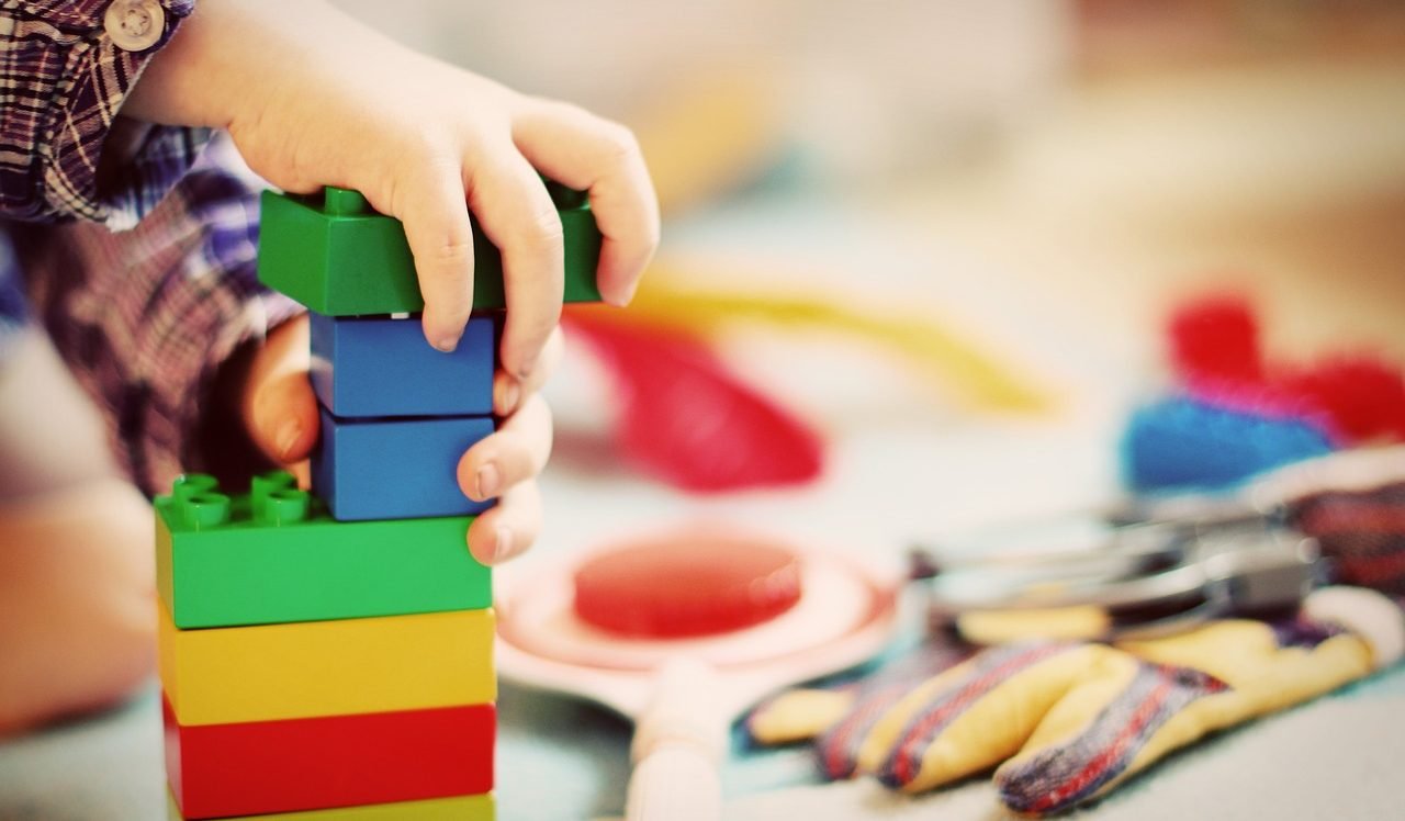 Kinderhände bauen mit farbigen Bausteinen
